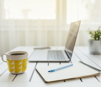 A computer on a desk with a cup of coffee